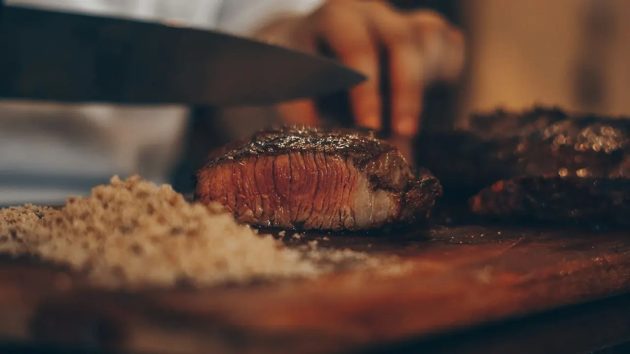 A butcher slicing meat on a wooden board