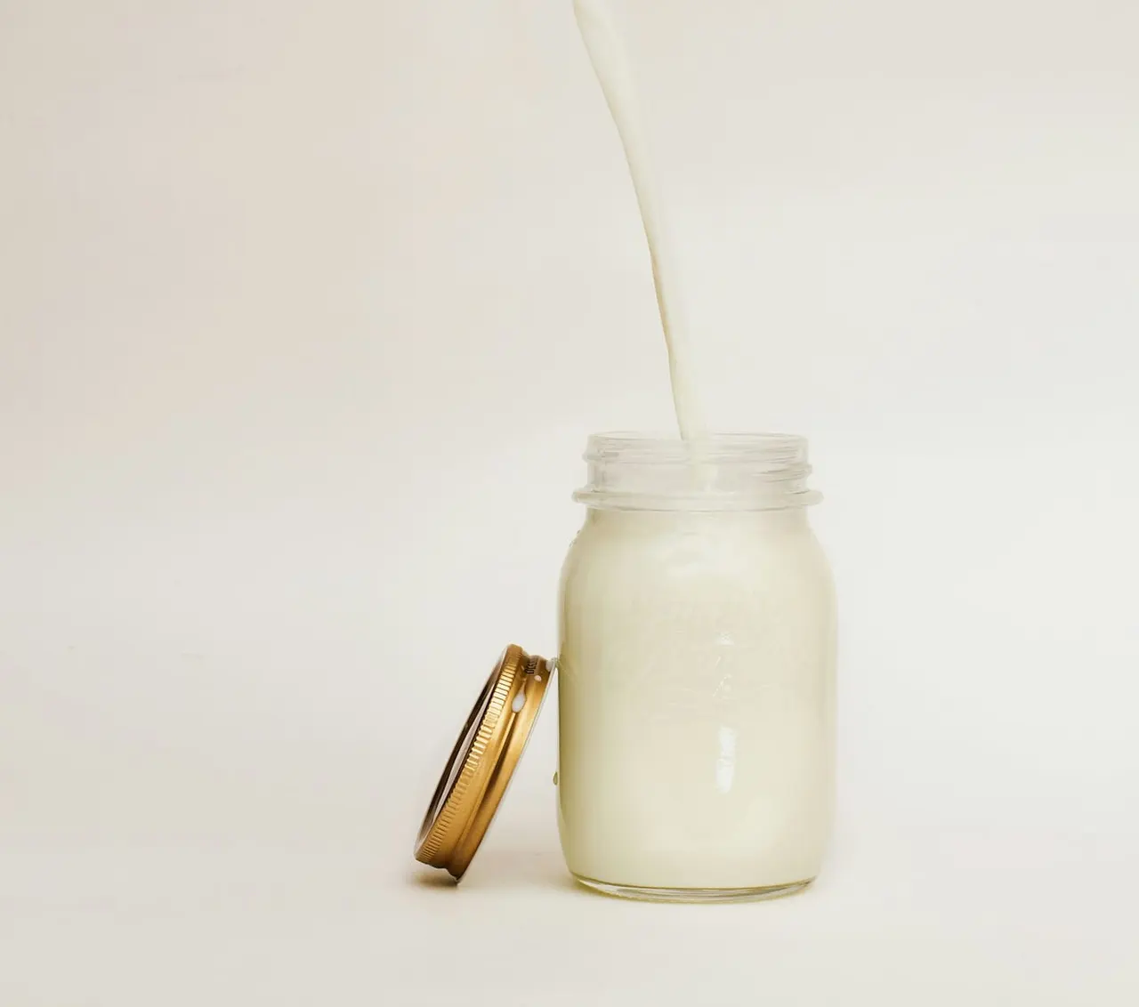 A drink being poured into a glass jar